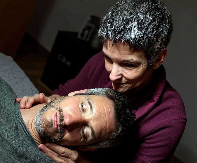 Close-up Fotografie: Eine Expertin in einem blauen Blazer führt die Hand eines Klienten zur korrekten Atembewegung, ein Biofeedback-Gerät steht auf dem Tisch.